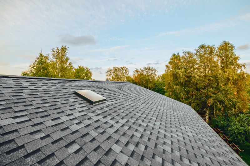 Close up of grey shingle roof with small square skylight